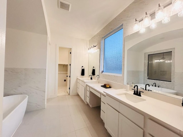 bathroom featuring vanity, a washtub, tile patterned floors, and tile walls