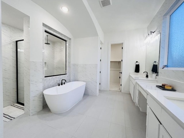 bathroom featuring vanity, plus walk in shower, and tile walls