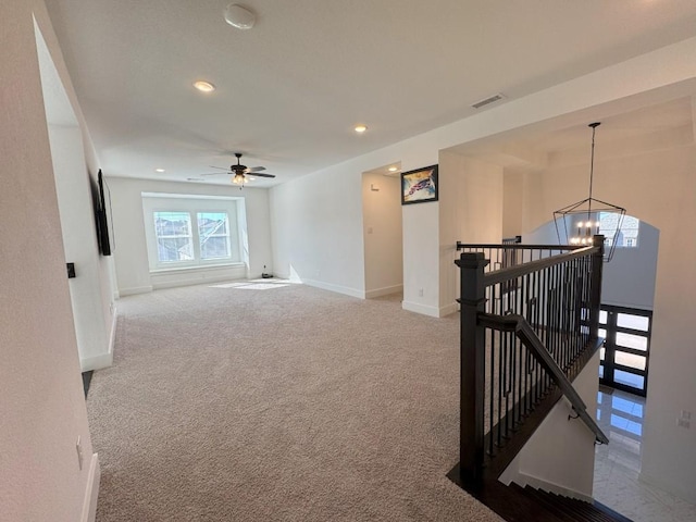 spare room featuring ceiling fan with notable chandelier and light colored carpet