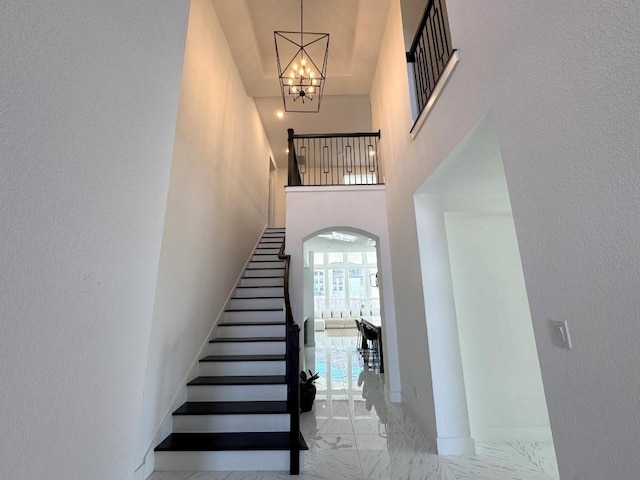 stairway with an inviting chandelier and a towering ceiling