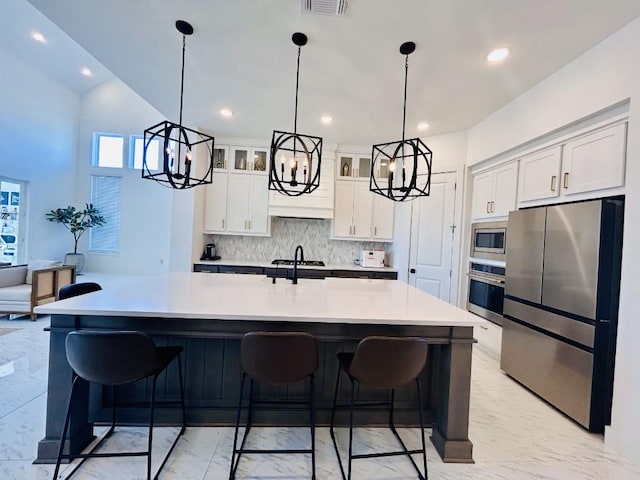 kitchen with appliances with stainless steel finishes, a breakfast bar area, white cabinets, and decorative backsplash