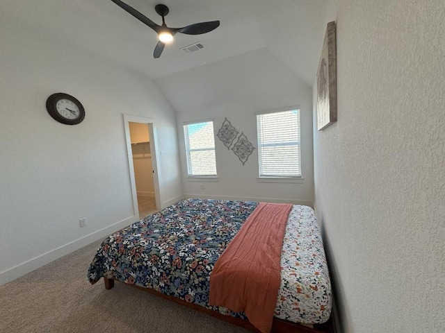 bedroom with a walk in closet, vaulted ceiling, ceiling fan, and carpet flooring