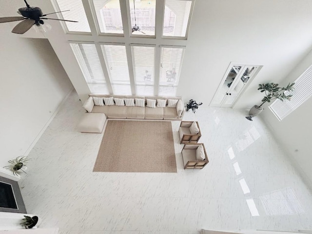 living room with ceiling fan and a towering ceiling