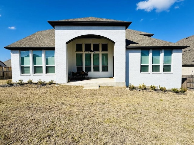 rear view of house featuring ceiling fan, a patio, and a lawn