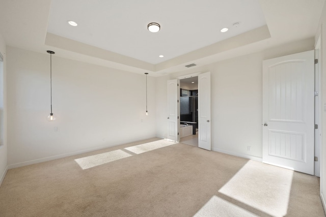 unfurnished bedroom with a tray ceiling and light colored carpet