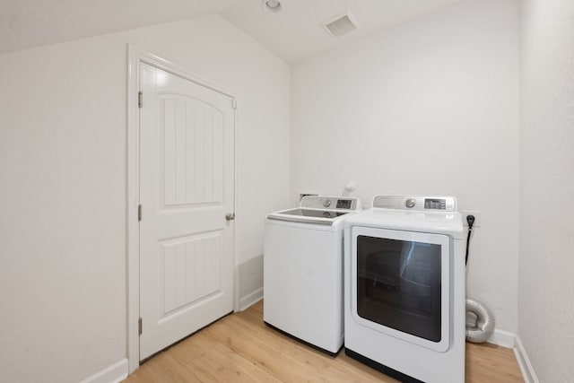 laundry area featuring washing machine and dryer and light hardwood / wood-style floors