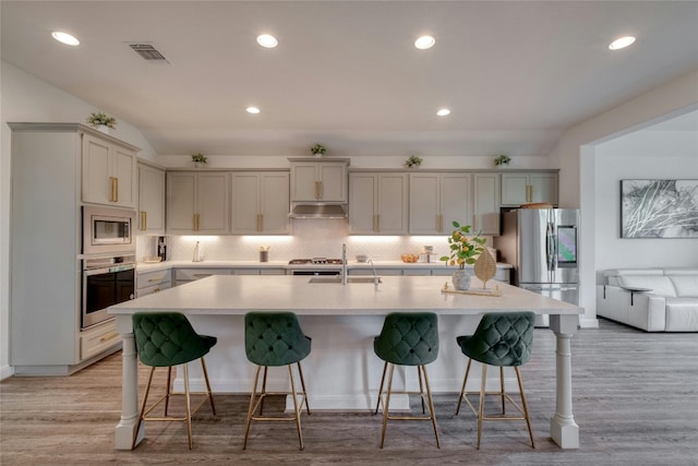 kitchen with appliances with stainless steel finishes, a kitchen island with sink, and a kitchen bar