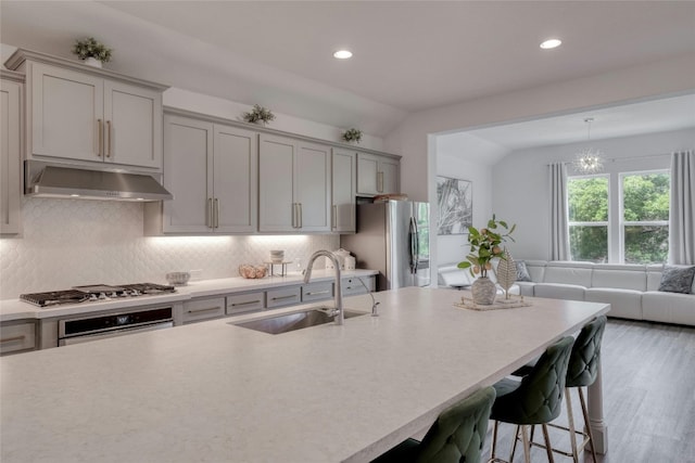 kitchen with tasteful backsplash, sink, vaulted ceiling, and stainless steel appliances