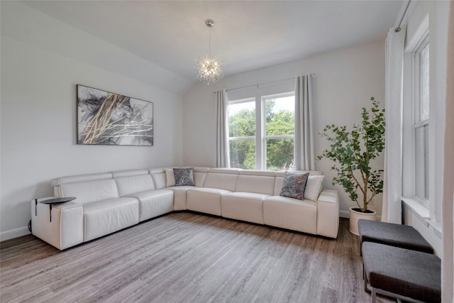 living room featuring hardwood / wood-style flooring, vaulted ceiling, and an inviting chandelier