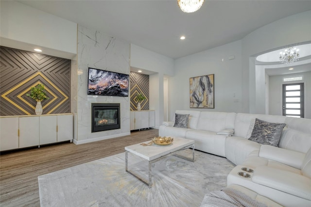 living room with an inviting chandelier, a premium fireplace, and light hardwood / wood-style floors