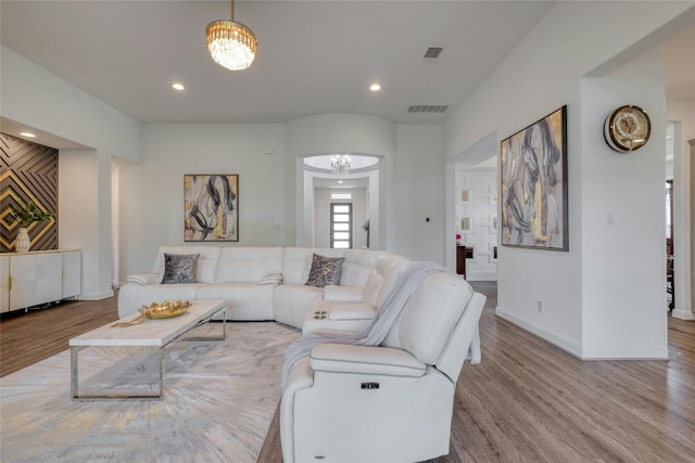 living room featuring light wood-type flooring and a notable chandelier