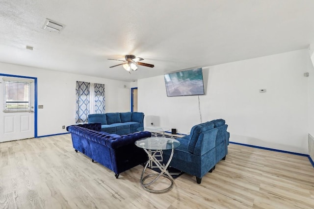 living room with ceiling fan, light hardwood / wood-style flooring, and a textured ceiling