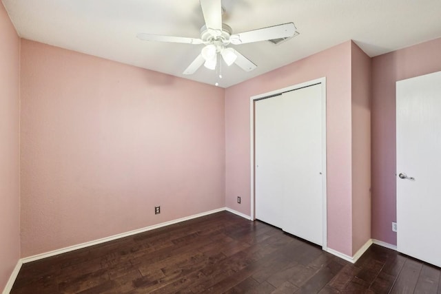 unfurnished bedroom with dark hardwood / wood-style flooring, a closet, and ceiling fan