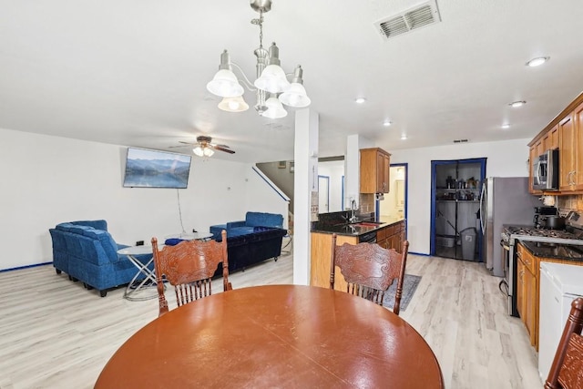 dining room featuring ceiling fan with notable chandelier, sink, and light hardwood / wood-style flooring