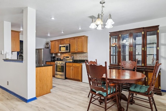 dining area with an inviting chandelier, sink, and light wood-type flooring