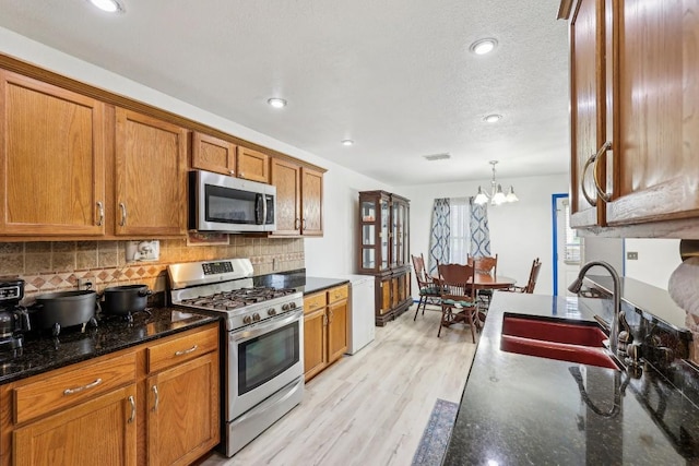 kitchen featuring sink, hanging light fixtures, a notable chandelier, stainless steel appliances, and backsplash