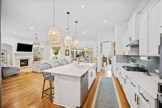 kitchen featuring decorative light fixtures, sink, white cabinets, a kitchen bar, and a center island with sink