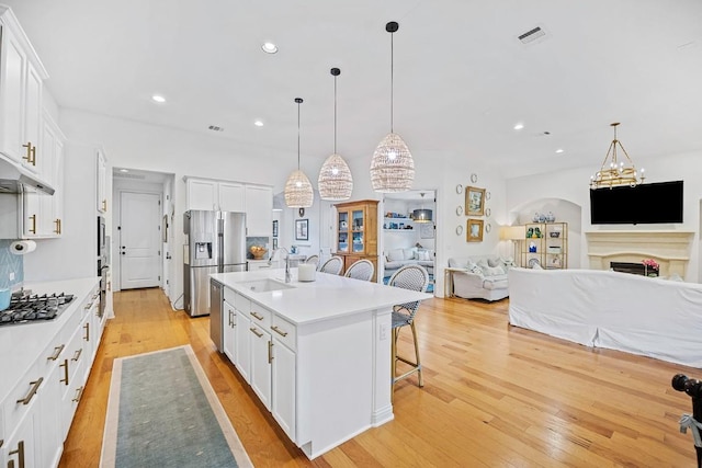 kitchen featuring stainless steel appliances, a breakfast bar, a center island with sink, and white cabinets