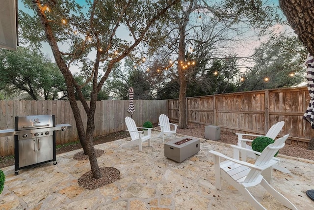 patio terrace at dusk featuring area for grilling and a fire pit