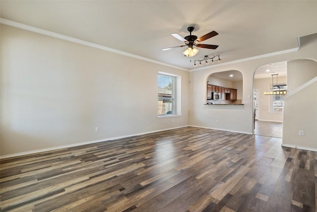 empty room with dark wood-type flooring, ceiling fan, ornamental molding, and a wealth of natural light