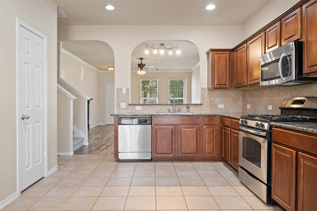 kitchen with sink, light tile patterned floors, appliances with stainless steel finishes, tasteful backsplash, and ornamental molding