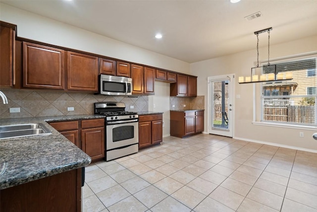 kitchen with sink, hanging light fixtures, light tile patterned floors, stainless steel appliances, and decorative backsplash