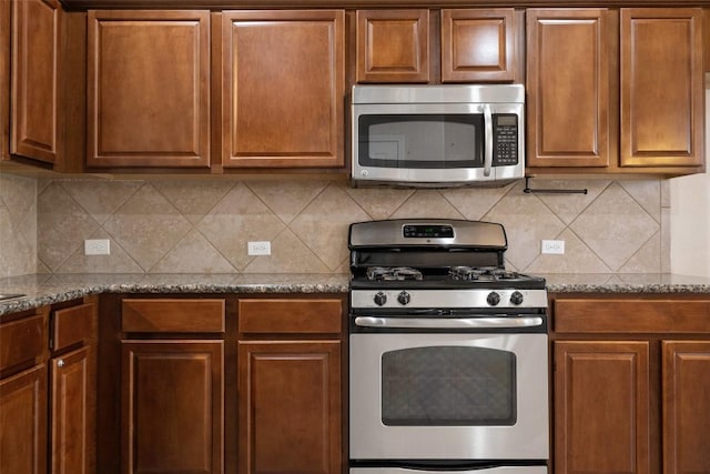 kitchen featuring tasteful backsplash, stainless steel appliances, and dark stone countertops