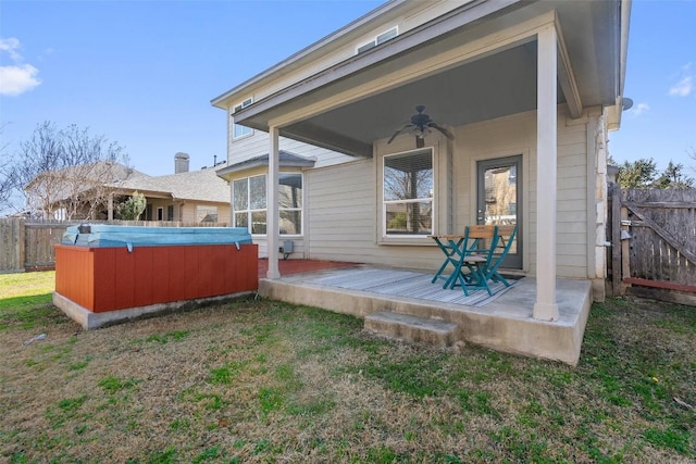 back of property with ceiling fan, a yard, a hot tub, and a deck