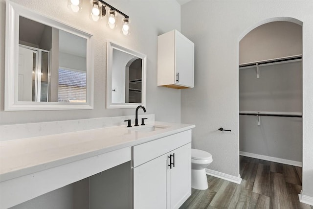 bathroom with hardwood / wood-style flooring, vanity, walk in shower, and toilet