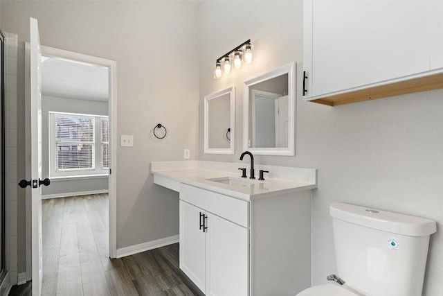 bathroom with hardwood / wood-style flooring, vanity, a shower with door, and toilet