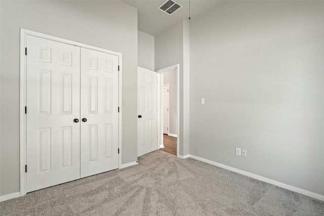 unfurnished bedroom with light colored carpet and a closet