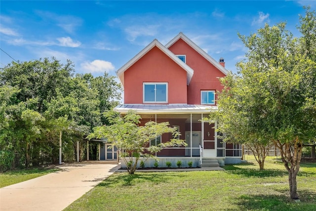 view of front of house featuring a front yard, a sunroom, and a storage unit