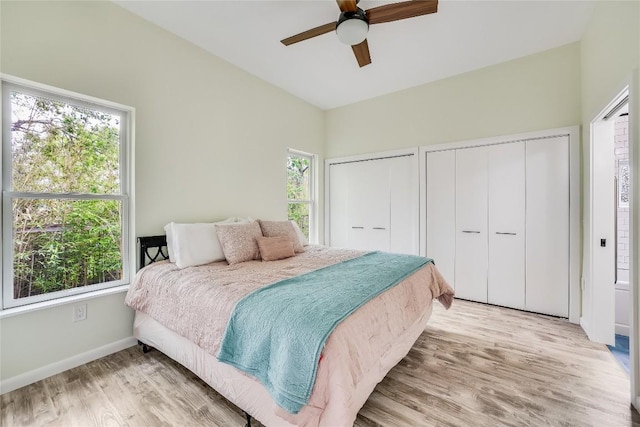 bedroom featuring ceiling fan, light wood-type flooring, and two closets