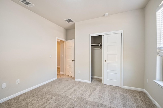 unfurnished bedroom featuring light colored carpet and a closet