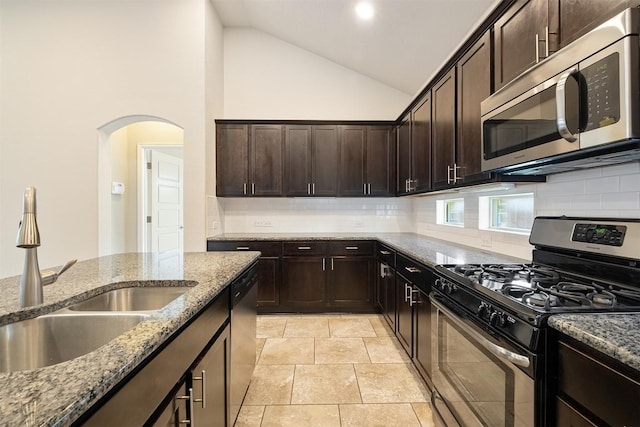 kitchen featuring light stone counters, dark brown cabinetry, appliances with stainless steel finishes, and sink