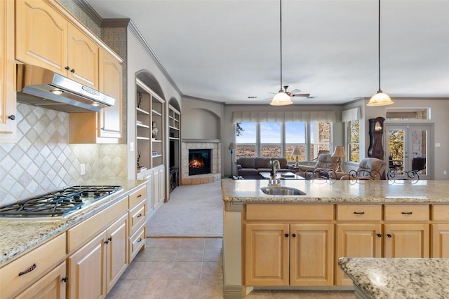 kitchen with pendant lighting, sink, a fireplace, stainless steel gas cooktop, and light brown cabinetry