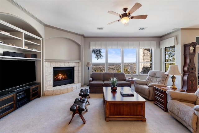 living room featuring ceiling fan, ornamental molding, a fireplace, and light carpet