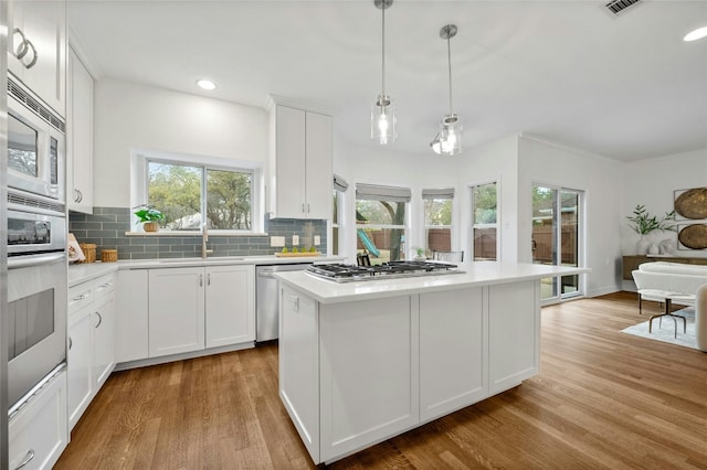 kitchen featuring sink, white cabinets, decorative backsplash, a center island, and stainless steel appliances