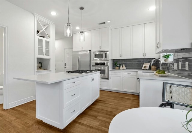 kitchen featuring sink, white cabinetry, hanging light fixtures, a kitchen island, and stainless steel appliances