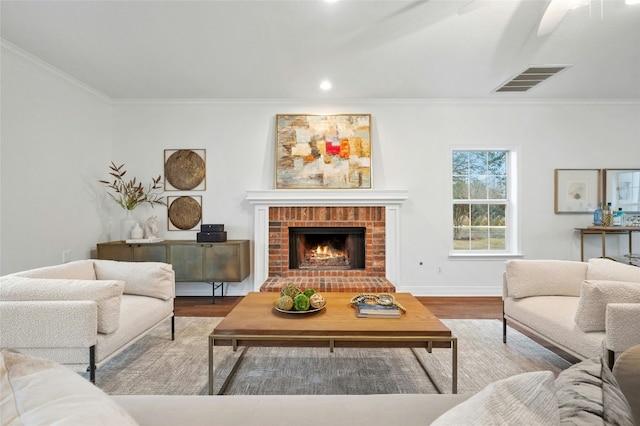 living room with crown molding, ceiling fan, wood-type flooring, and a fireplace