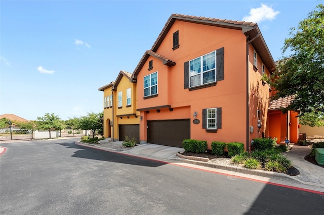 view of front of property featuring a garage, a tile roof, driveway, and stucco siding