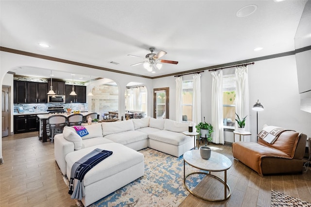 living room with crown molding, light hardwood / wood-style flooring, and ceiling fan