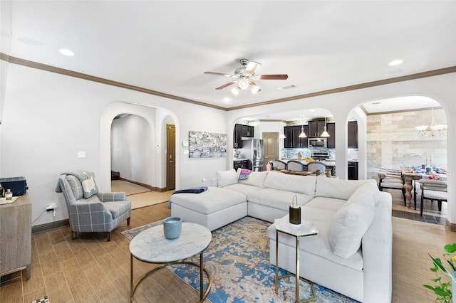 living area featuring arched walkways, wood finished floors, baseboards, and ceiling fan with notable chandelier