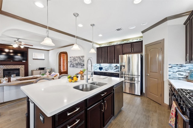 kitchen featuring decorative light fixtures, sink, a kitchen island with sink, dark brown cabinetry, and stainless steel appliances