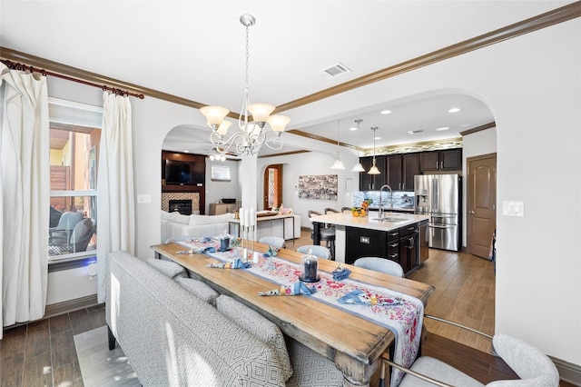 dining room with ornamental molding, sink, a chandelier, and dark hardwood / wood-style flooring