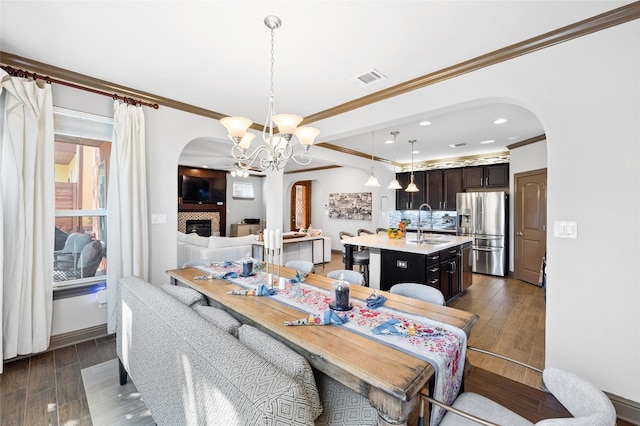 12332 Terraza Cir, Austin, TX 78726 - dining space with arched walkways, dark wood finished floors, ornamental molding, a chandelier, and a fireplace