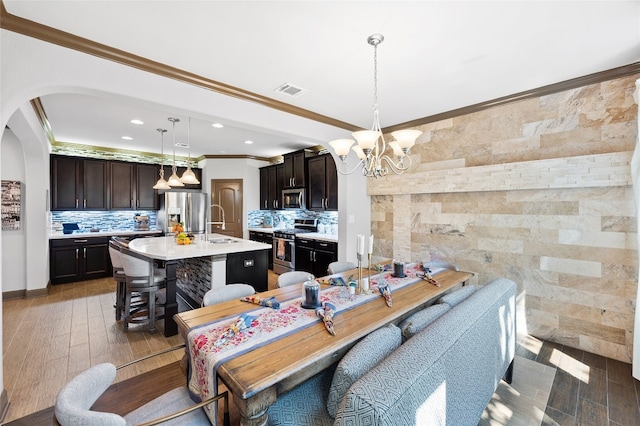 dining room featuring ornamental molding, arched walkways, a chandelier, and wood finished floors