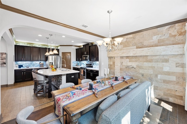 12332 Terraza Cir, Austin, TX 78726 - dining area featuring ornamental molding, arched walkways, a chandelier, light wood-type flooring, and recessed lighting