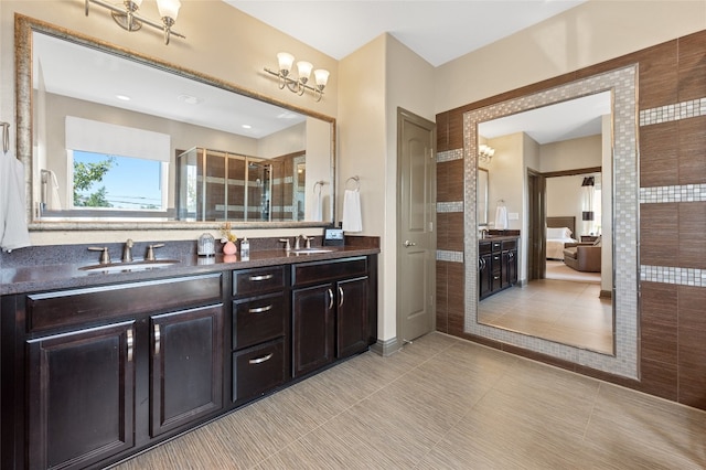 bathroom with vanity, a shower with shower door, and a notable chandelier