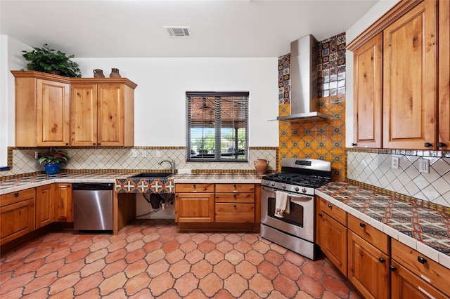 kitchen featuring sink, decorative backsplash, stainless steel appliances, and wall chimney exhaust hood